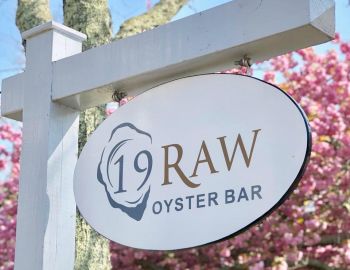 19 Raw Oyster Bar Sign of 19 Raw Oyster Bar in front of some pink trees